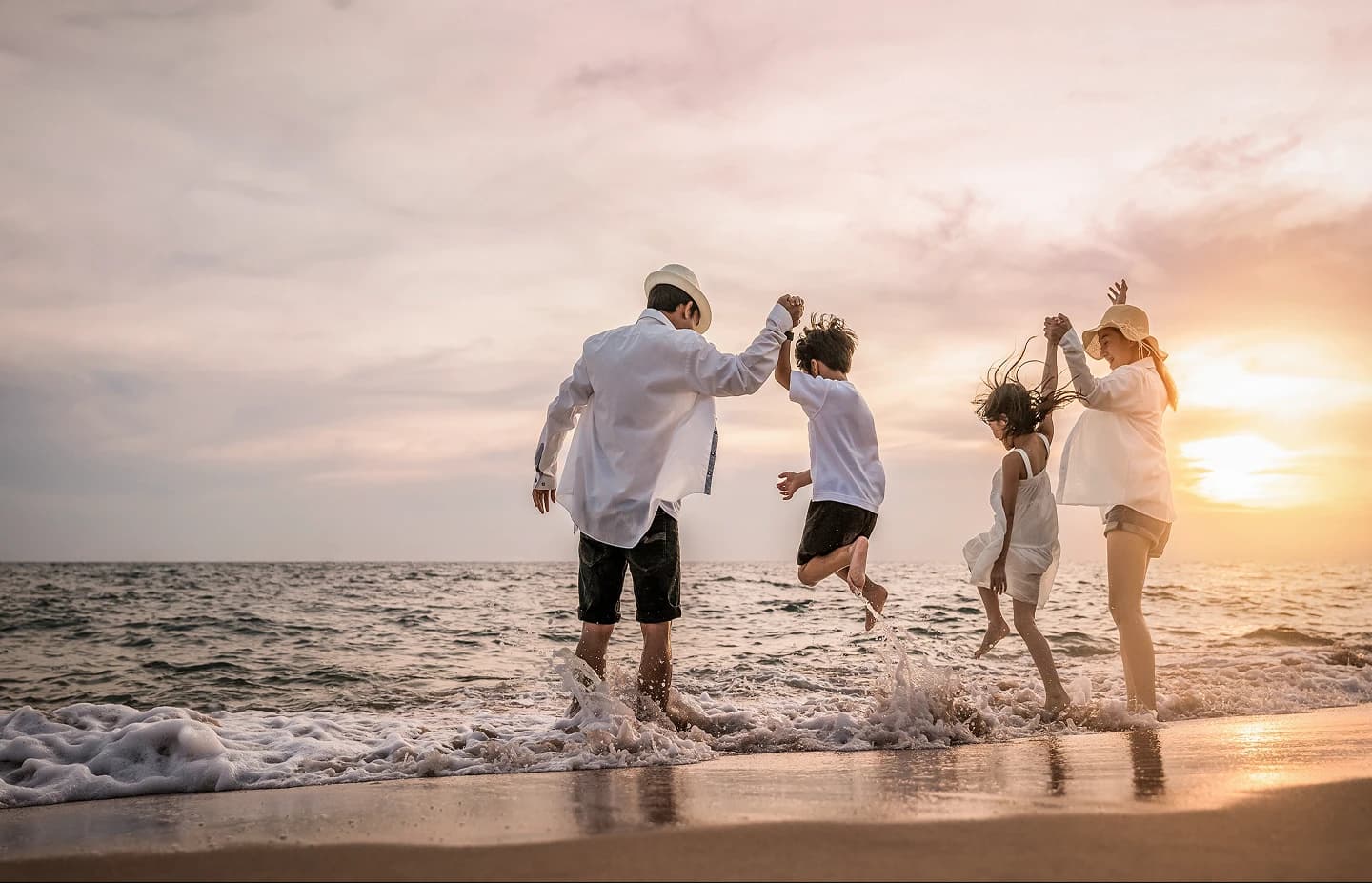 Family playing at the beach during sunset
